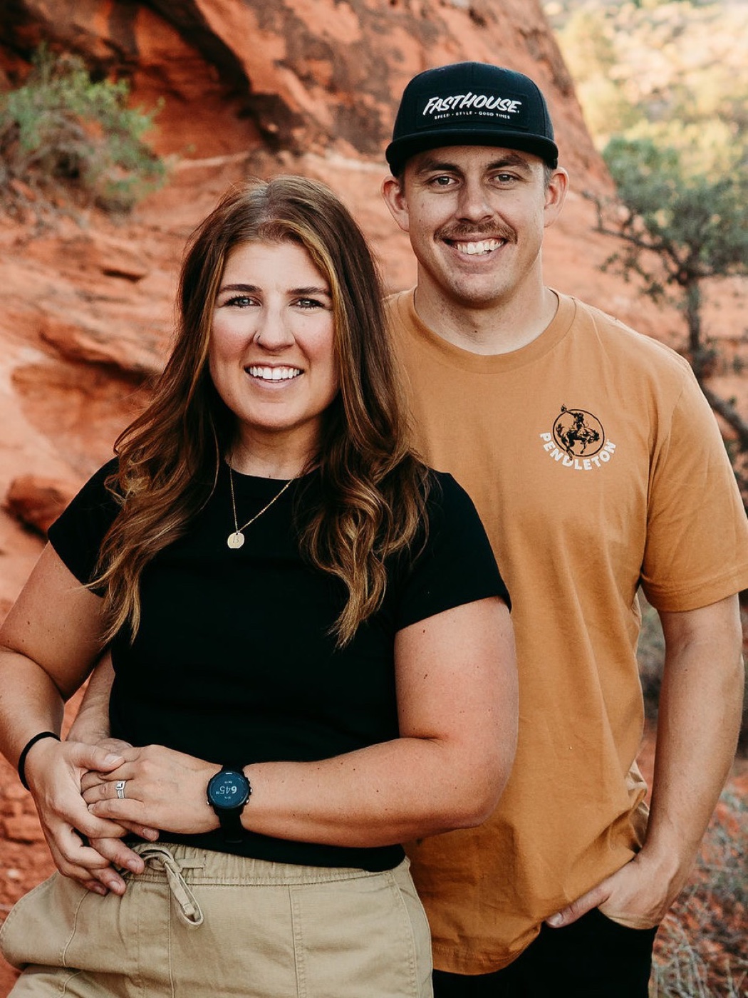Andrew and Kelsey Priest standing together in the red rock outside Hurricane, Utah