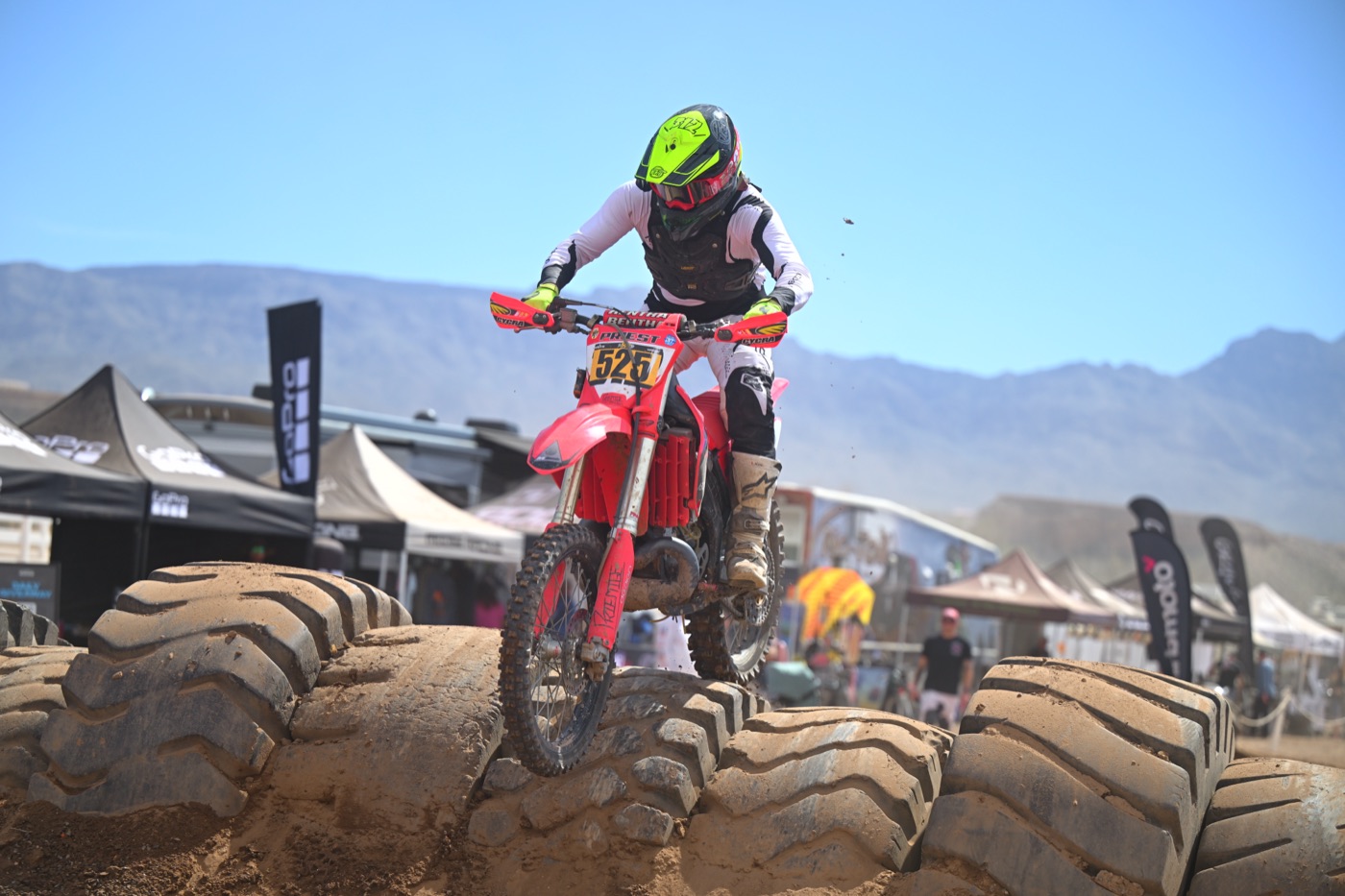 A dirt bike mid-jump over a berm at a desert race